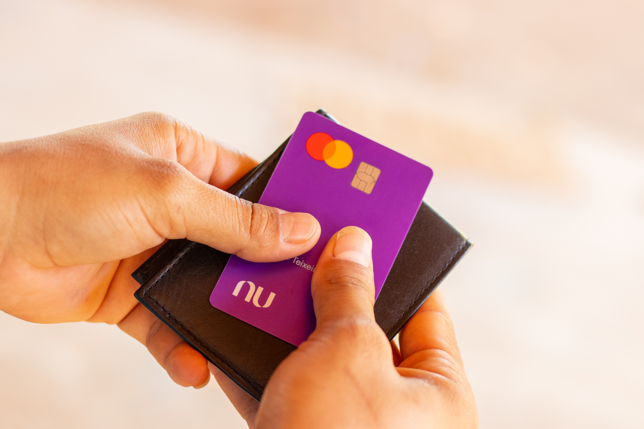 Homem segurando cartão Nubank.