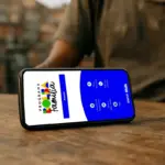 Celular sobre mesa de madeira com a tela do aplicativo Bolsa Família